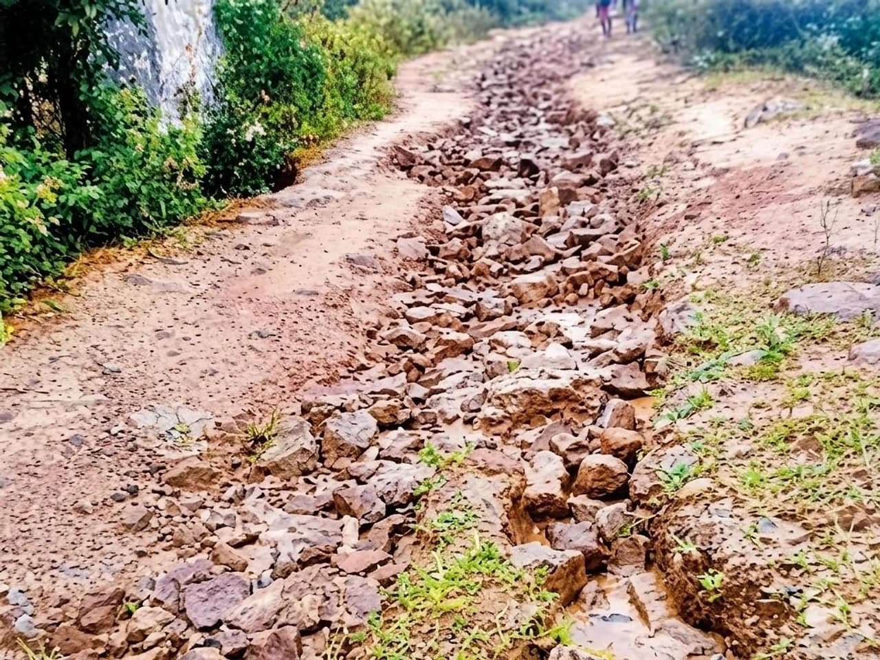 వర్షానికి మట్టి కొట్టుకుపోయి.. రాళ్లు తేలిన రహదా